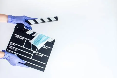 Hands in blue disposable rubber gloves holding openned movie clapper Stock Photos