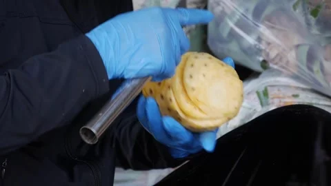 Hands in blue gloves peel and trim a pineapple with a knife at a market stall. F Stock Footage 341408592