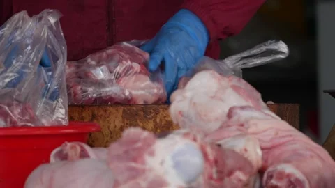 Hands in blue gloves place raw meat into a clear bag at a market counter. Food h Stock-Footage 342140104