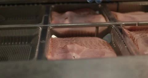 Hands in blue gloves placing sliced ham into a packaging mold at a food factory Vídeo Stock 339991531