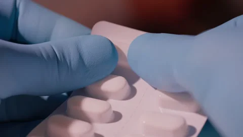 Hands in Blue Gloves Pushing White Pills Out of Blister Pack Stock Footage 338363613