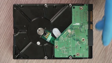 Hands in blue gloves remove and flip the green electronic board from open HDD Stock Footage 124629694