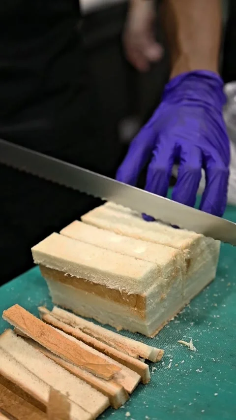 Hands with blue gloves slicing bread on a cutting board 스톡 동영상 310815357
