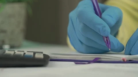 Hands in blue gloves write in pad and calculates closeup Stock-Footage 134997818