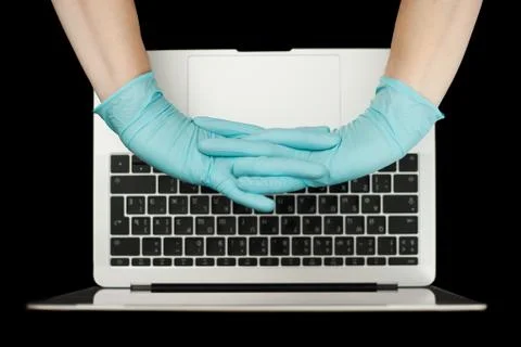 Hands in blue protective gloves typing on laptop keyboard. Top view. Coronavi Stock Photos