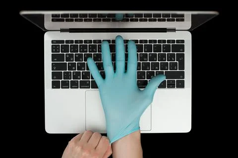 Hands in blue protective gloves typing on laptop keyboard. Top view. Coronavi Stock Photos