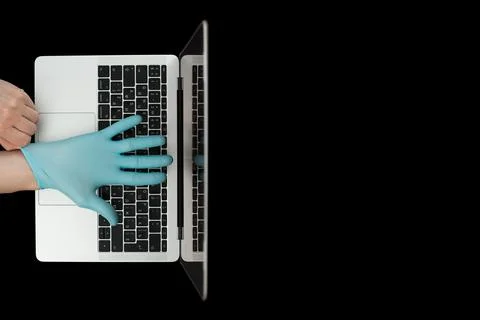 Hands in blue protective gloves typing on laptop keyboard. Top view. Coronavi Stock Photos