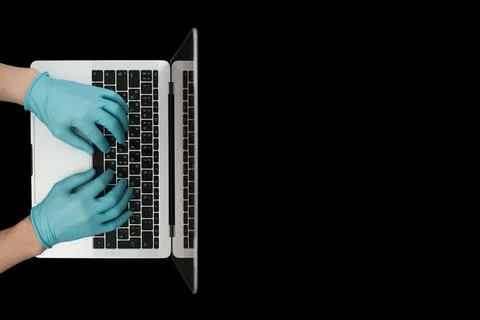 Hands in blue protective gloves typing on laptop keyboard. Top view. Coronavi Stock Photos