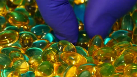 Hands in blue rubber gloves pick up fish oil capsules. Stock Footage 148163161
