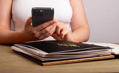 Hands with botany application on smartphone and herbarium book with dry plant Stock Photos
