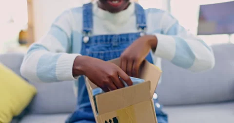Hands, box and ecommerce with a black woman opening a clothes package on a sofa Stock Footage 247552734