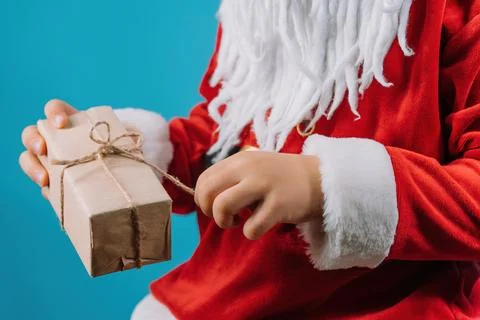Hands of boy in Santa's costume pulling on string of wrapped gift box. 写真素材