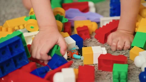 Hands boy searching through scattered colorful blocks pile on carpet tactile Stock Footage 331948494