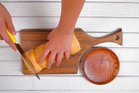 Hands boy slicing roll cake buttercream filling on white wooden background Stock Photos