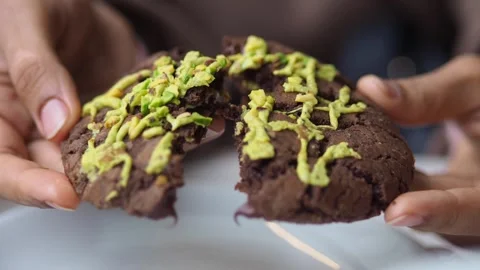 Hands break delicious chocolate chip cookie with pistachio topping revealin.. Stockbeeldmateriaal 331835851