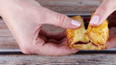 Hands break delicious pastry stuffed with cherries. Breakfast and desert concept 動画素材 138158693
