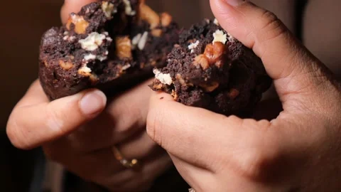 Hands break fresh chocolate walnut cookie in half revealing soft fudgy text.. Stock Footage 331915229