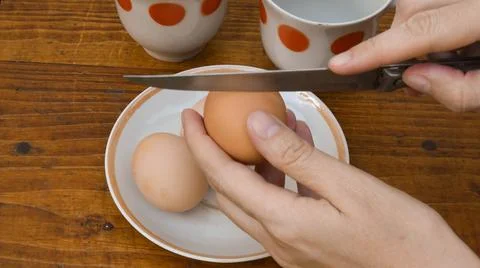 Hands break raw egg with kitchen knife Foto stock