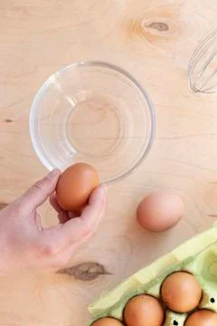 Hands break a raw egg. Stir the protein with the yolk. Glass bowl on a wooden Stock Photos