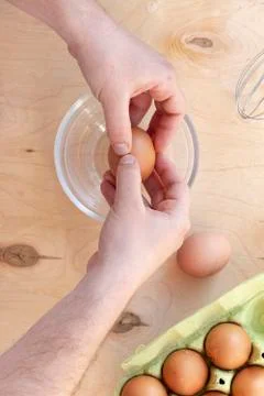 Hands break a raw egg. Stir the protein with the yolk. Glass bowl on a wooden Stock Photos