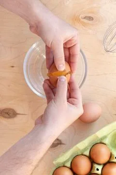 Hands break a raw egg. Stir the protein with the yolk. Glass bowl on a wooden Stock Photos
