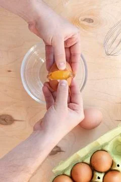 Hands break a raw egg. Stir the protein with the yolk. Glass bowl on a wooden Stock Photos
