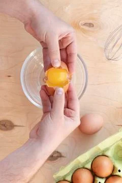 Hands break a raw egg. Stir the protein with the yolk. Glass bowl on a wooden Stock Photos