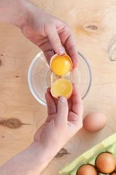 Hands break a raw egg. Stir the protein with the yolk. Glass bowl on a wooden Stock Photos