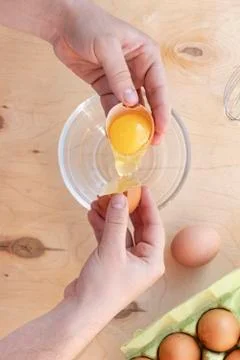 Hands break a raw egg. Stir the protein with the yolk. Glass bowl on a wooden Stock Photos