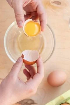 Hands break a raw egg. Stir the protein with the yolk. Glass bowl on a wooden Stock Photos