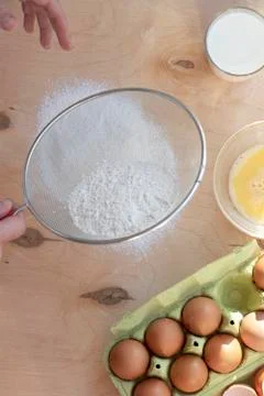 Hands break a raw egg. Stir the protein with the yolk. Sifting flour through  Stock Photos
