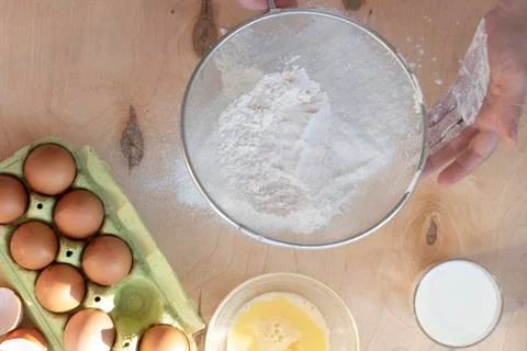 Hands break a raw egg. Stir the protein with the yolk. Sifting flour through  Stock Photos