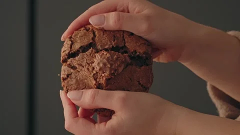 Hands breaking chocolate cookie in half indoors close up Stock Footage 328896635