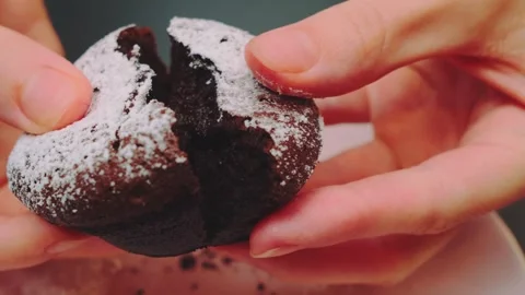 Hands Breaking a Chocolate Muffin Indoors on a Light Surface 库存影片 342881781