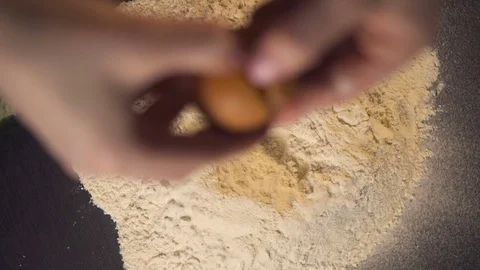 Hands breaking cracking a raw egg over flour, baking concept slow motion Stock Footage