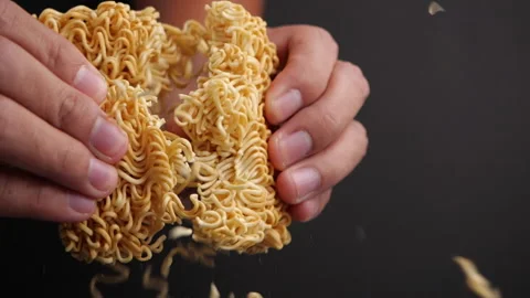 Hands breaking a crispy instant noodles in slow motion on dark background Video stock 131693204