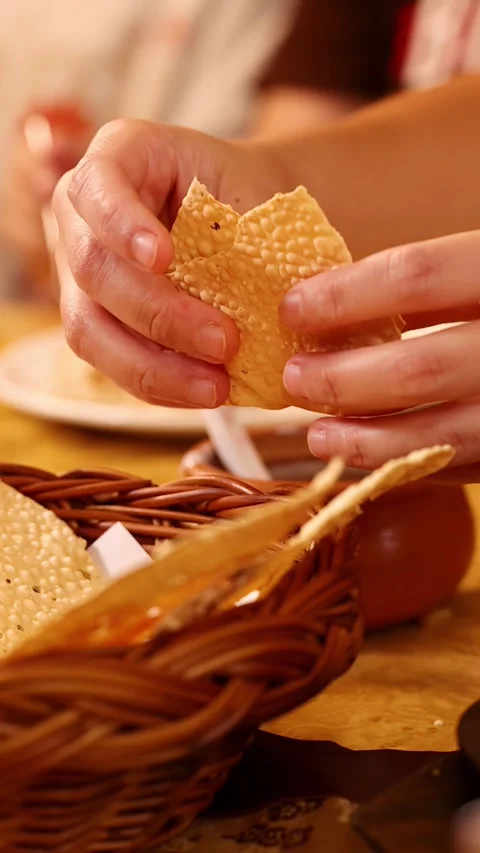 Hands Breaking Crispy Papadum Bread Over a Wicker Basket Stock Footage 339752350