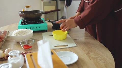 Hands breaking fresh chicken egg yolk into bowl with fork to prepare fried rice Stock Footage 342678720
