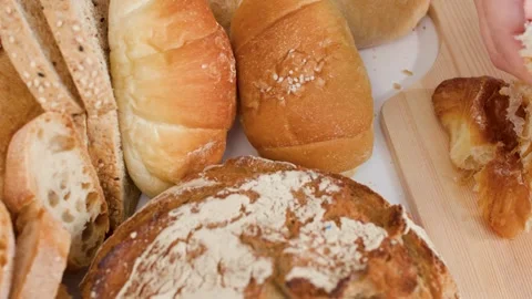 Hands Breaking Fresh Croissant Beside Assorted Artisan Bakery Breads Stock Footage 337535313