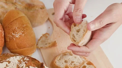 Hands Breaking Fresh Crusty Bread Over Wooden Cutting Board Stock Footage 337394846