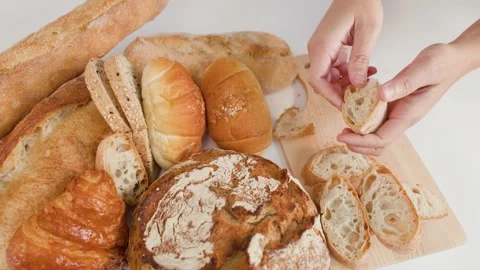 Hands Breaking Fresh Sourdough Bread Over Assorted Bakery Selection Stock Footage 337748615