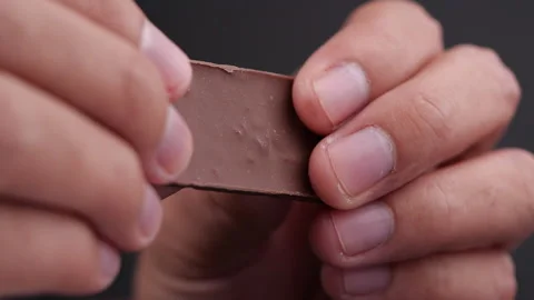 Hands breaking a piece of dark chocolate in slow motion Stock Footage 131693210