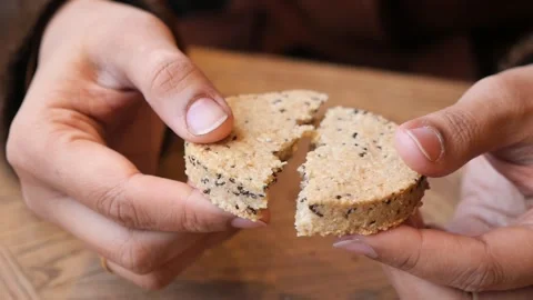 Hands breaking a round cookie in a cafe setting Stock Footage 330093042