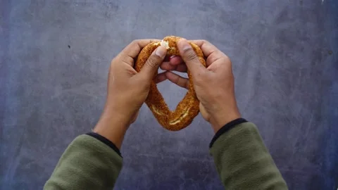 Hands Breaking a Traditional Turkish Simit Bread Ring Stock Footage 328443343