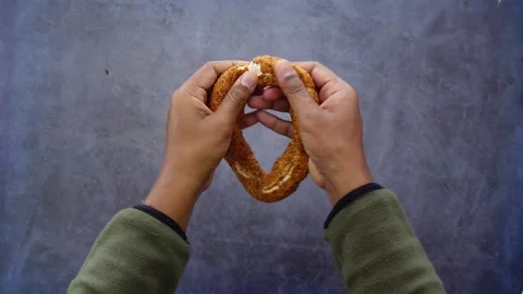 Hands breaking traditional turkish simit bread on stone background shot in .. Stock Footage 331934491