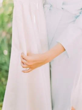 The hands of the bride are touching the silk wedding dress. Close-up view. Stock Photos
