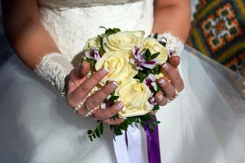 Hands of a bride with a bouquet. Light from the window. Wedding bouquet rose. Stock Photos