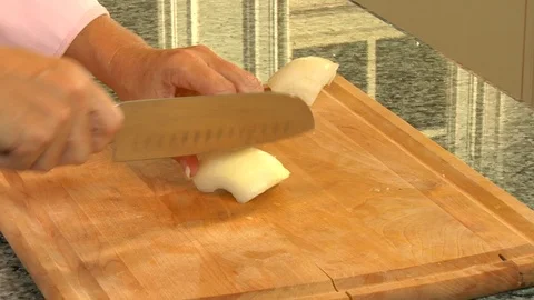 Hands in brightly lit kitchen slicing white onions Stock Footage 123732603