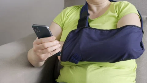 Hands with broken arm wearing sling using smart phone Video stock 302890620