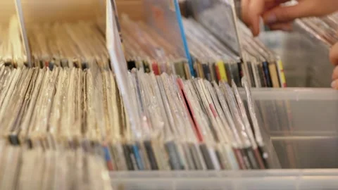 Hands browsing vinyl record collection in plastic crates, selecting vintage Stock Footage 344697929